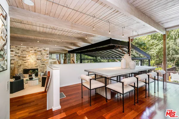 a dining hall with stainless steel appliances kitchen island granite countertop a table chairs and a large window