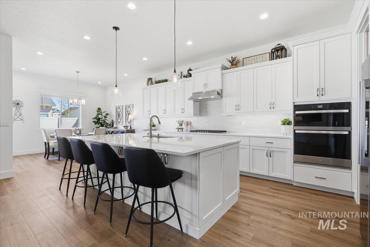 5512 North Ebony Way Meridian, ID 83646 - Photo 12 of 40 Kitchen featuring white cabinets, a breakfast bar, and a kitchen island with sink