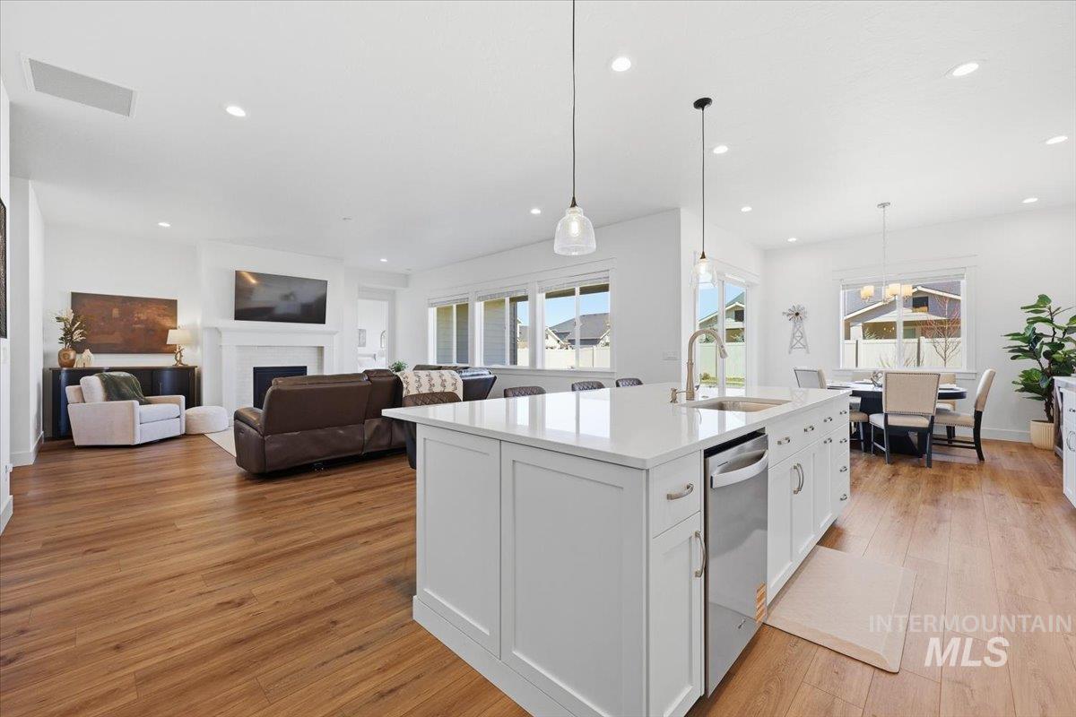 5512 North Ebony Way Meridian, ID 83646 - Photo 14 of 40 Kitchen with white cabinetry, a fireplace, light wood-style flooring, a kitchen island with sink, and light stone countertops