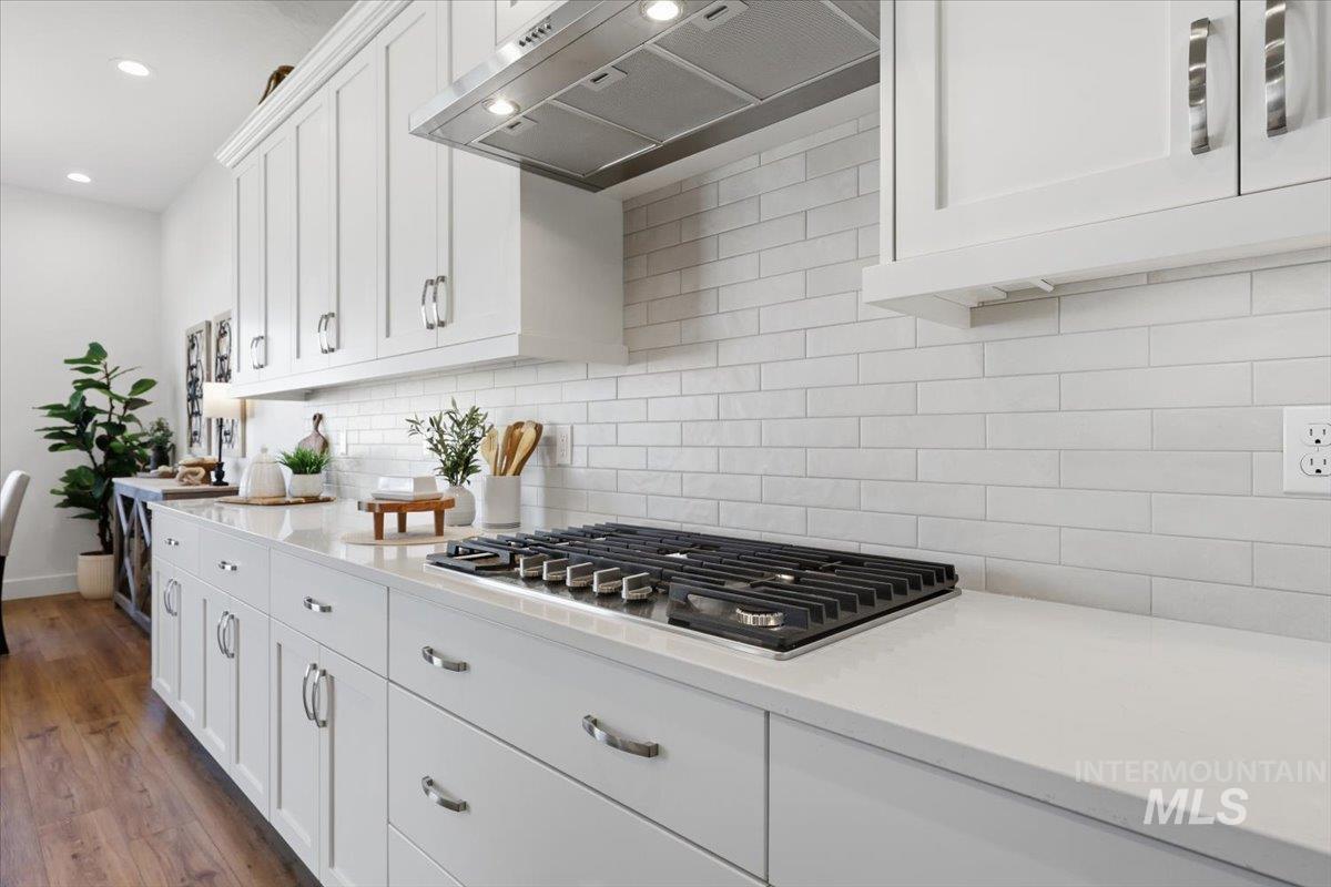 5512 North Ebony Way Meridian, ID 83646 - Photo 15 of 40 Kitchen with exhaust hood, white cabinets, stainless steel gas stovetop, light stone countertops, and recessed lighting