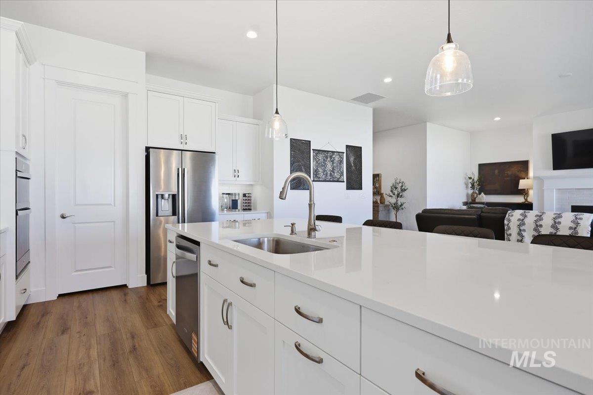5512 North Ebony Way Meridian, ID 83646 - Photo 16 of 40 Kitchen featuring white cabinets, a fireplace, light stone counters, and dark wood finished floors