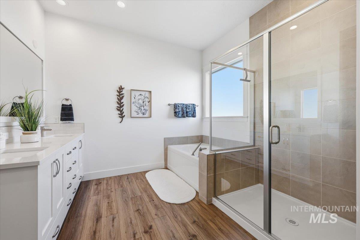 5512 North Ebony Way Meridian, ID 83646 - Photo 20 of 40 Bathroom featuring dark wood-style flooring, double vanity, a shower stall, a bath, and recessed lighting