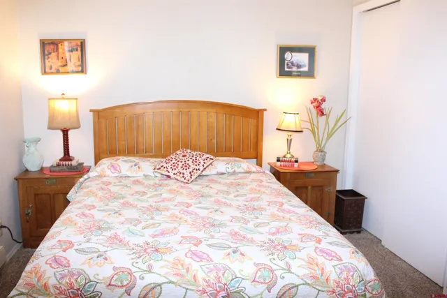 a bedroom with a bed and a lamp on dresser