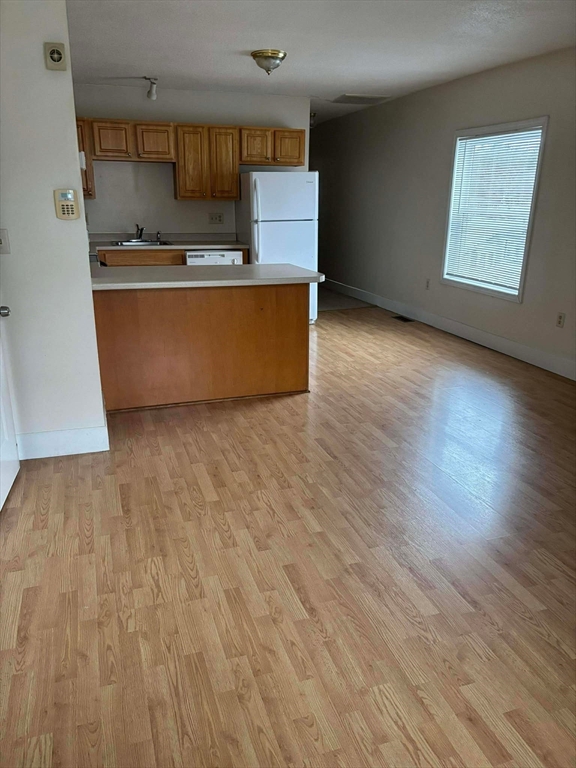 48 North Street, Unit 9 Gilbertville, MA 01031 - Photo 3 of 12 an empty room with wooden floor and kitchen view