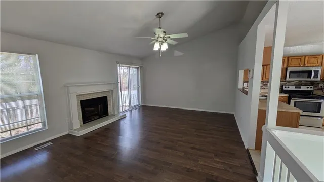 an empty room with wooden floor fireplace and windows