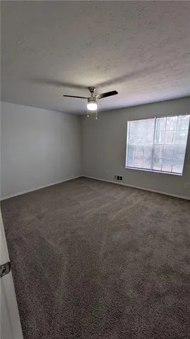 an empty room with a ceiling fan and windows