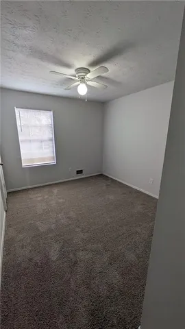 an empty room with a ceiling fan and window