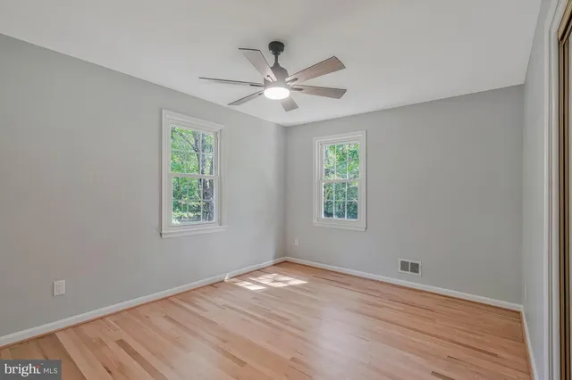 a view of empty room with wooden floor and fan