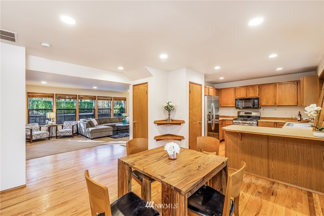 23511 Meridian Avenue South Bothell, WA 98021 - Photo 15 of 40 a open kitchen with stainless steel appliances granite countertop a stove top oven a dining table and chairs with wooden floor