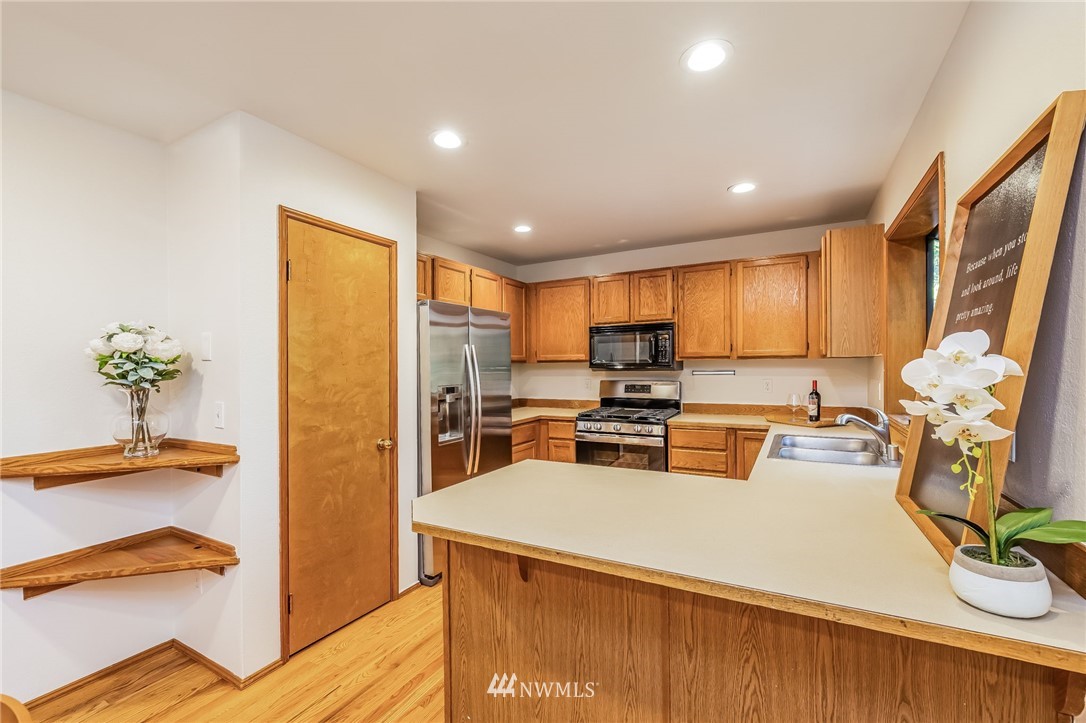 23511 Meridian Avenue South Bothell, WA 98021 - Photo 16 of 40 a kitchen with a refrigerator a stove top oven a sink a dining table and chairs