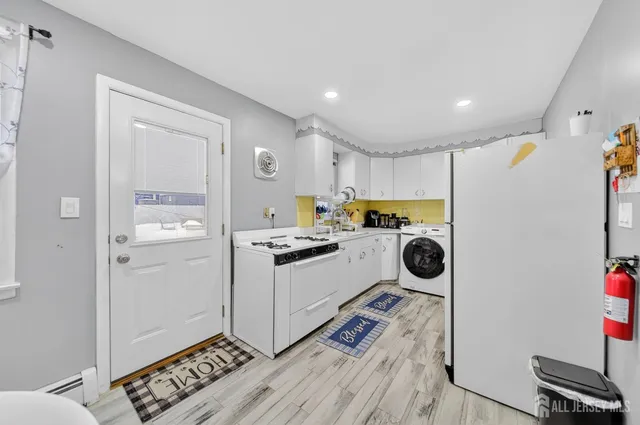 a living room with furniture a kitchen island a stove a refrigerator and a dining table with wooden floor