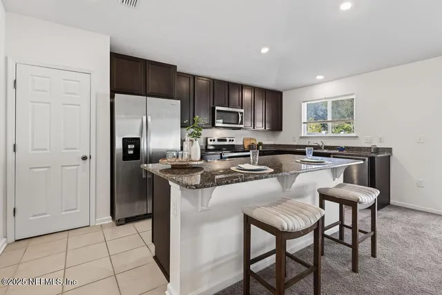 a kitchen with stainless steel appliances granite countertop a stove a sink a microwave a refrigerator and island