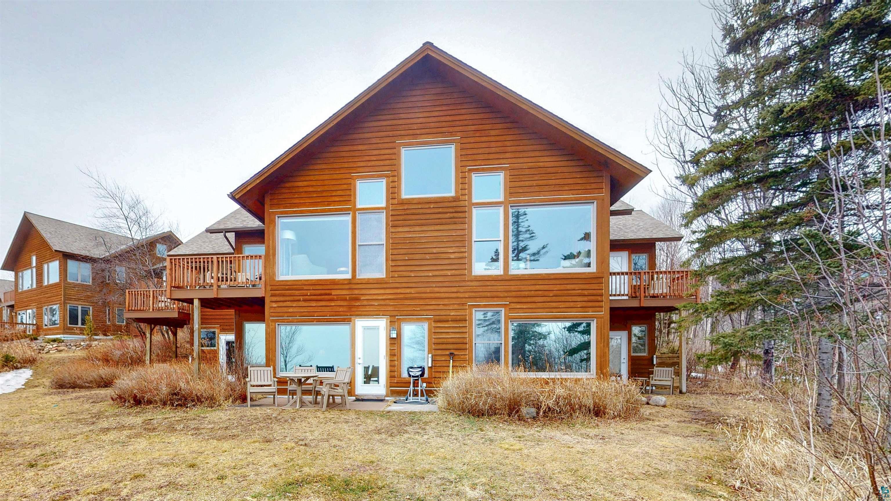 504-506 Poplar River Road, Unit 505 Lutsen, MN 55612 - Photo 21 of 39 Wood-sided exterior featuring multiple large windows, a ground-level patio, and an upper-level deck