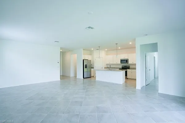 a view of kitchen with kitchen island stainless steel appliances refrigerator sink and cabinets
