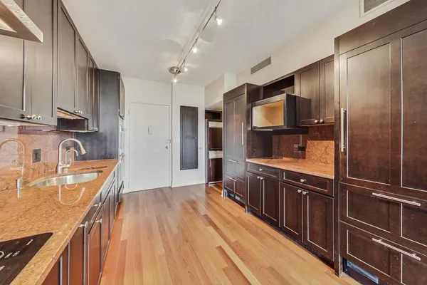 a kitchen with stainless steel appliances granite countertop a refrigerator a sink dishwasher a stove and white countertops with wooden floor