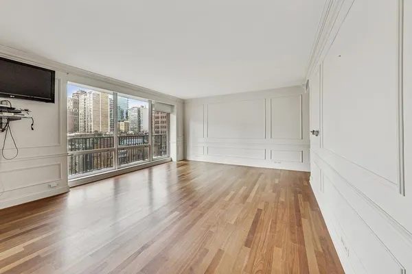 a view of empty room with wooden floor and fan