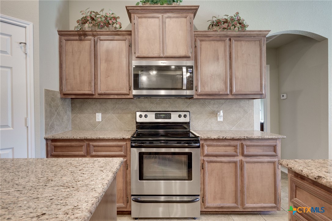 1467 County Road 4820 Kempner, TX 76539 - Photo 11 of 38 a kitchen with granite countertop a stove top oven microwave and cabinets