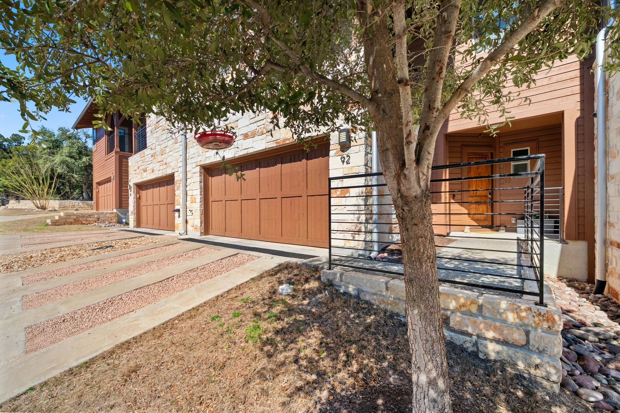 8110 Ranch Road 2222, Unit 92 Austin, TX 78730 - Photo 2 of 40 Stone and wood-sided exterior featuring two integrated garage doors