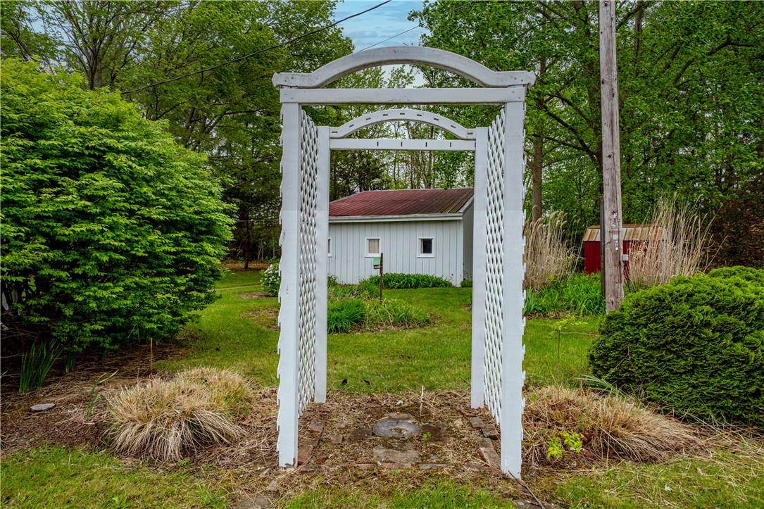 11296 Pansing Road Brookville, OH 45309 - Photo 35 of 53 A charming arbor entrance invites you into a serene yard with lush greenery and a quaint outbuilding.