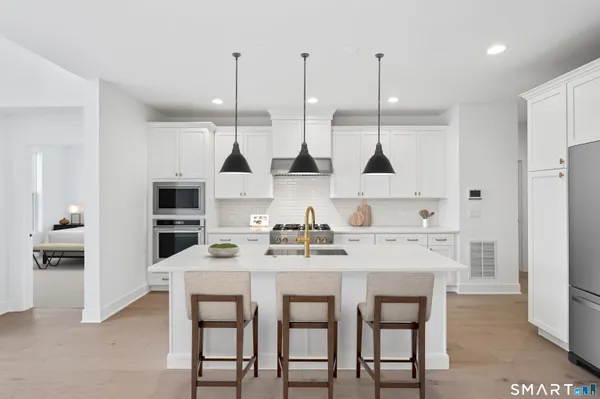 a kitchen with stainless steel appliances kitchen island granite countertop a dining table chairs and white cabinets