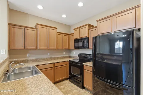 a kitchen with stainless steel appliances granite countertop a refrigerator a sink and white cabinets with wooden floor