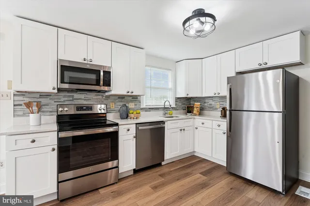 a kitchen with cabinets stainless steel appliances a sink and wooden floor