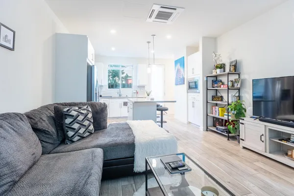 a living room with furniture kitchen view and a wooden floor