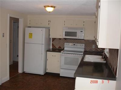 Undisclosed Address Harwich, MA 02645 - Photo 9 of 9 a kitchen with a refrigerator stove and white cabinets