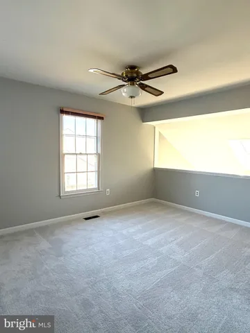an empty room with windows and ceiling fan