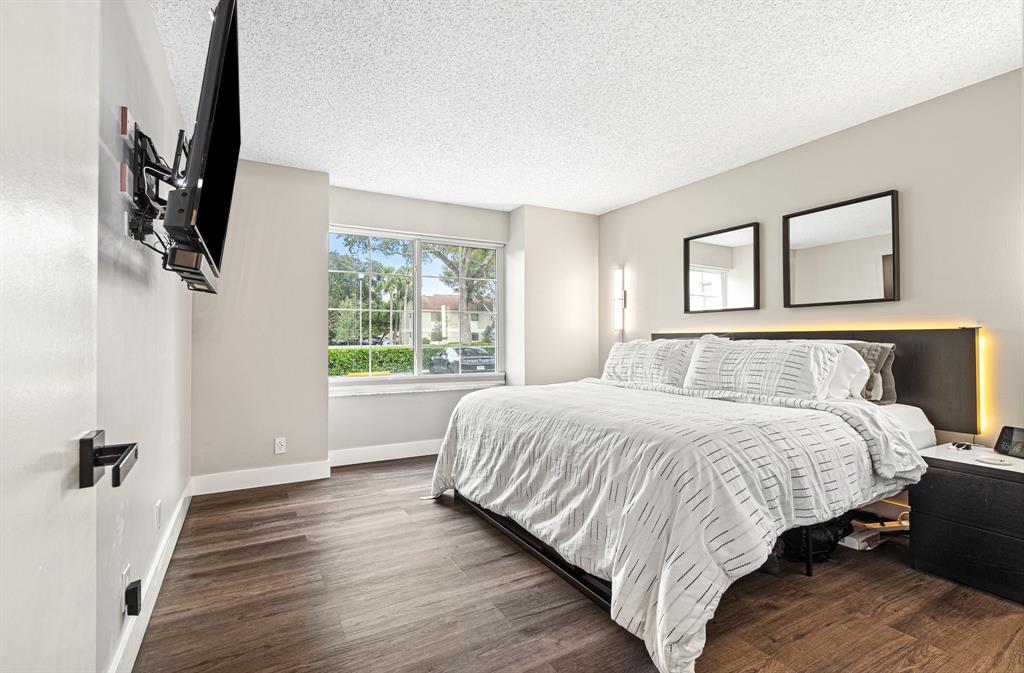 4620 West McNab Road, Unit B1 Pompano Beach, FL 33069 - Photo 22 of 36 a bedroom with a large bed and a flat tv screen on a dresser