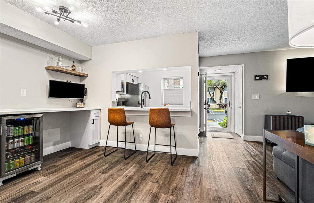 4620 West McNab Road, Unit B1 Pompano Beach, FL 33069 - Photo 8 of 36 a living room with furniture a flat screen tv and kitchen view