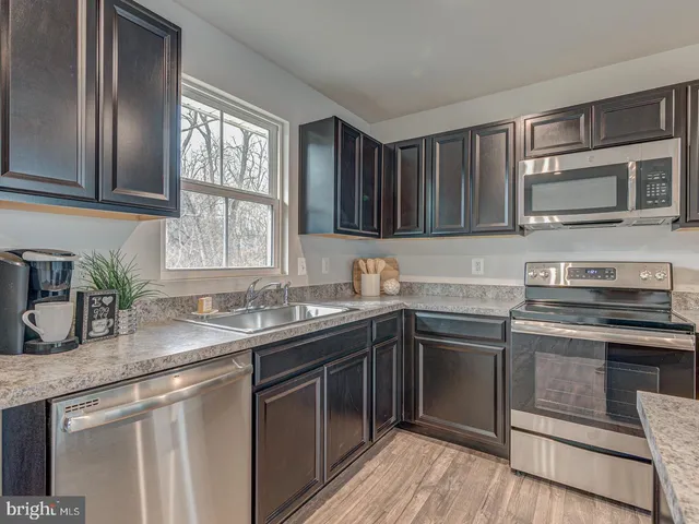 a kitchen with stainless steel appliances granite countertop a sink stove microwave and refrigerator