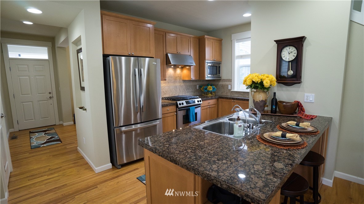 662 Lyons Avenue Northeast Renton, WA 98059 - Photo 10 of 28 a kitchen with stainless steel appliances granite countertop a refrigerator a stove and a sink with wooden floor