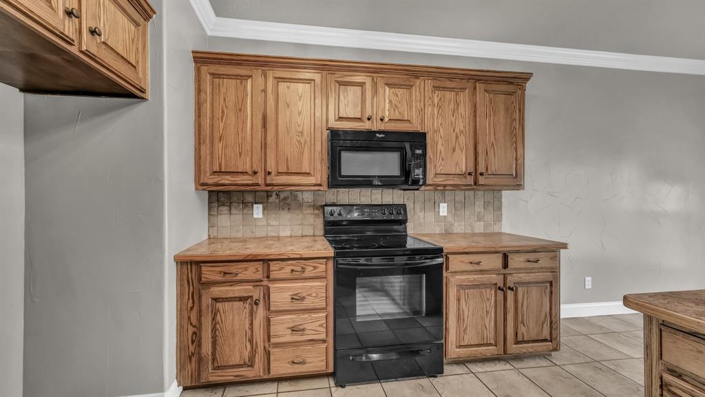 1106 Owl Street Decatur, TX 76234 - Photo 22 of 40 a kitchen with stainless steel appliances granite countertop a stove top oven microwave and cabinets