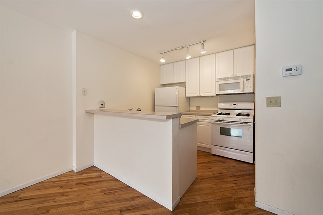 944 West Grace Street, Unit E202 Chicago, IL 60613 - Photo 4 of 10 a kitchen with white cabinets and white appliances