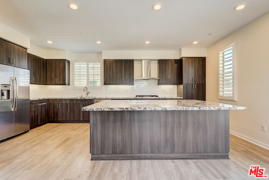 202 Paramount Irvine, CA 92618 - Photo 4 of 32 a kitchen with kitchen island granite countertop wooden cabinets a refrigerator and a sink