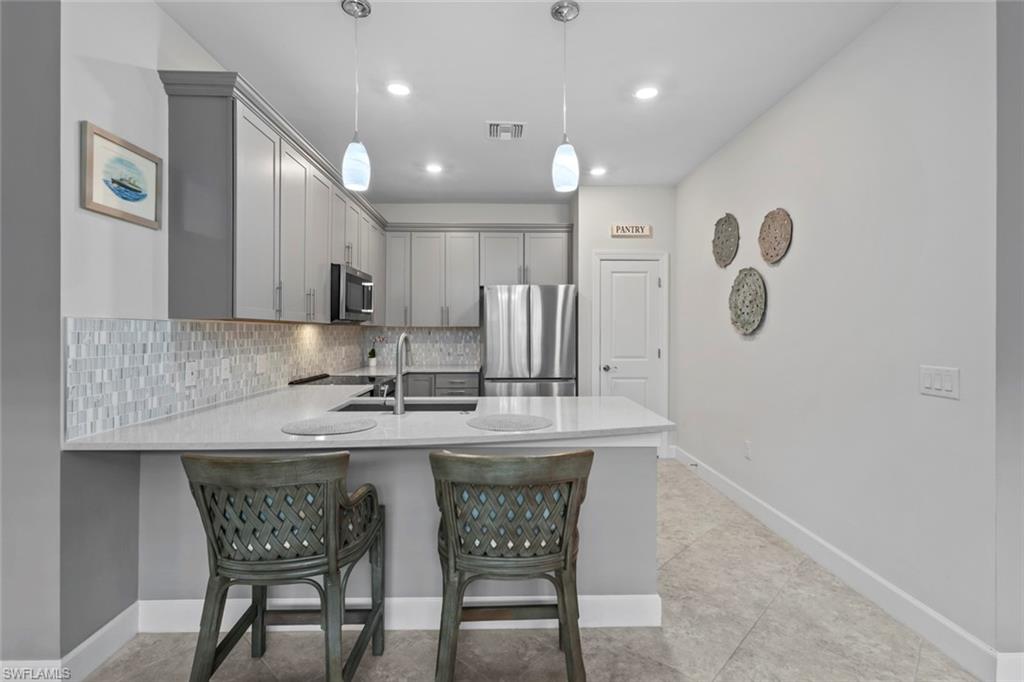 5825 Mayflower Way Ave Maria, FL 34142 - Photo 10 of 50 a kitchen with kitchen island a dining table chairs cabinets and a sink