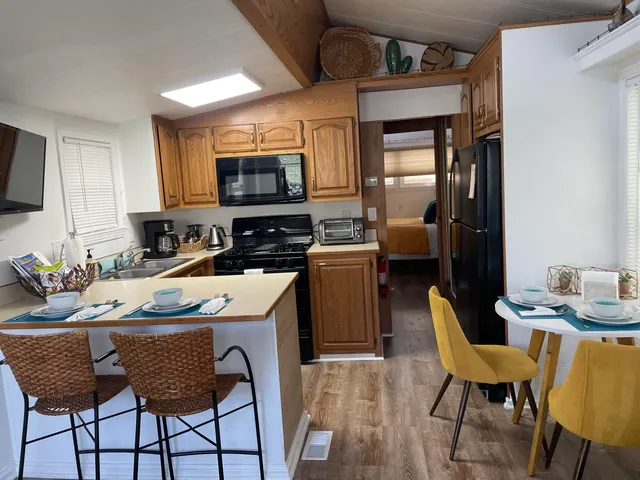 a kitchen with stainless steel appliances granite countertop a stove a sink dishwasher a dining table and chairs with wooden floor