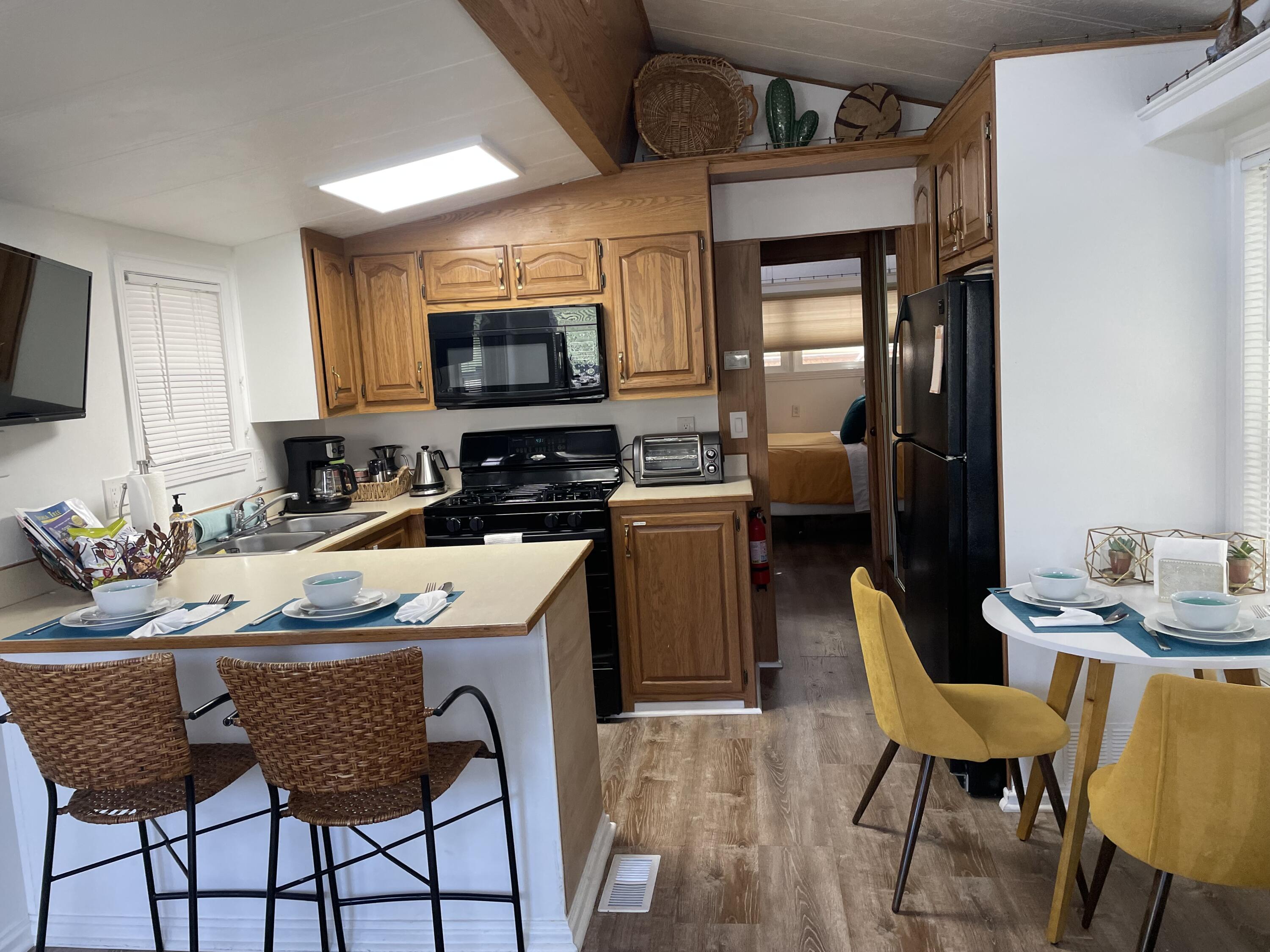 74711 Dillon Road, Unit 711 Desert Hot Springs, CA 92241 - Photo 3 of 35 a kitchen with stainless steel appliances granite countertop a stove a sink dishwasher a dining table and chairs with wooden floor
