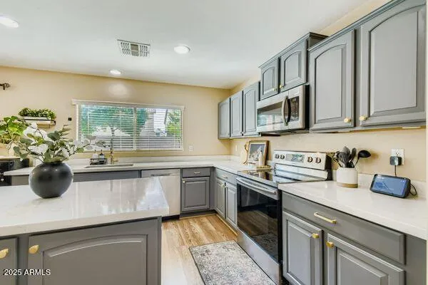 a room with stainless steel appliances kitchen island granite countertop furniture and a wooden floor
