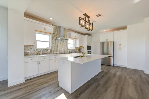 a large kitchen with a lot of counter space and wooden floor