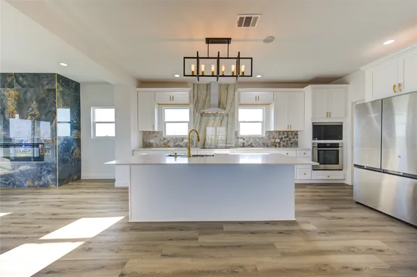 a large kitchen with kitchen island a stove a refrigerator and cabinets
