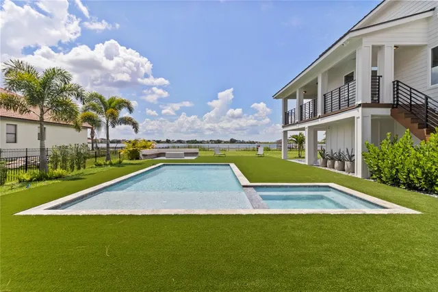 a view of swimming pool with lawn chairs and a big yard