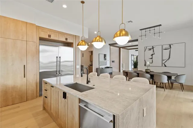 a large kitchen with granite countertop a sink a clock and a chandelier