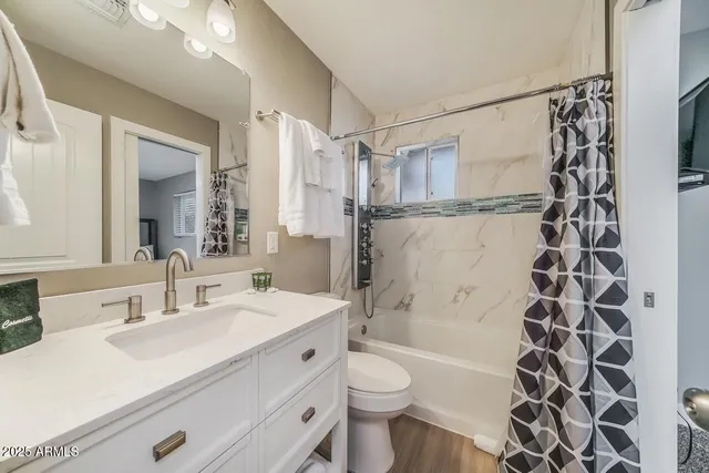 a bathroom with a sink a toilet a shower curtain and a mirror