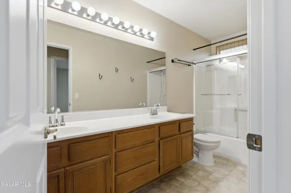 a bathroom with a double vanity sink toilet mirror and shower