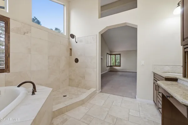 a bathroom with a granite countertop sink a bathtub and shower