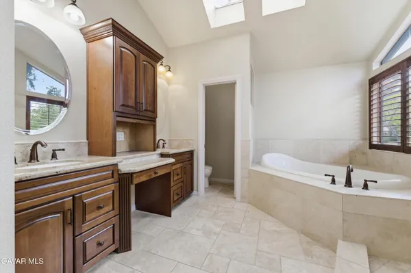 a spacious bathroom with a tub sink and mirror