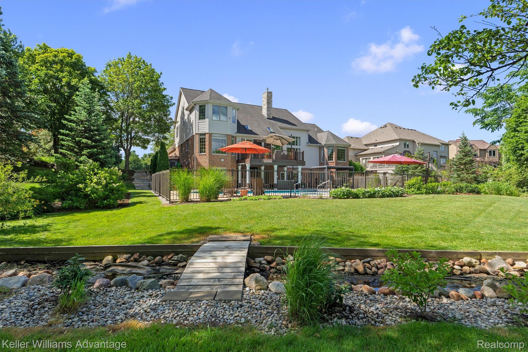22878 Tree Top Court South Lyon, MI 48178 - Photo 57 of 75 Rear exterior featuring an inground swimming pool, extensive lawn, and a deck with direct access from the house