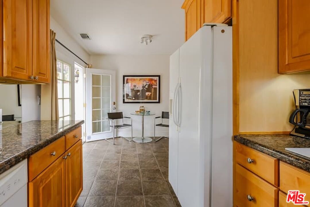 1203 South Rimpau Boulevard Los Angeles, CA 90019 - Photo 6 of 21 a kitchen with stainless steel appliances granite countertop a refrigerator and a stove top oven